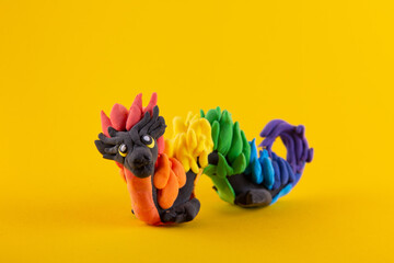Hand made modeling clay dragon on yellow background. Copy space for text
