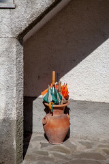 Decor of old Italian streets. Clay pot with umbrellas against the wall of the house.
