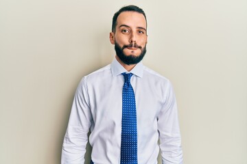 Young man with beard wearing business tie puffing cheeks with funny face. mouth inflated with air, crazy expression.