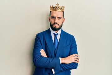 Young business man with beard wearing king crown skeptic and nervous, frowning upset because of problem. negative person.