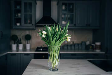 Vase of white tulips in a modern kitchen. Home concept with spring flowers.