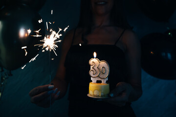 Elegant woman holding a cake with candle celebrating her 30th birthday.