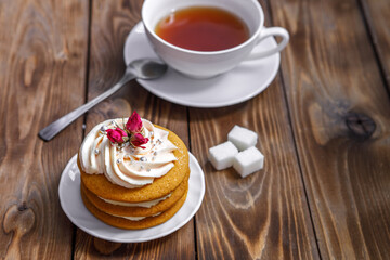 Sponge cake with cream, decorated with small flowers and a cup of tea.