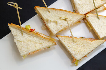 A plate of sandwiches on wooden skewers.