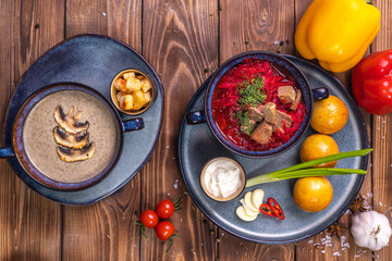 Soup in the assortment, tomatoes, spices on a brown wooden background.