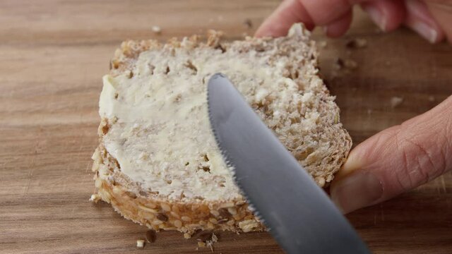 A bread and butter sandwich is greased with a knife.