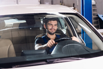 Car service workersits in a car and holds the wheel