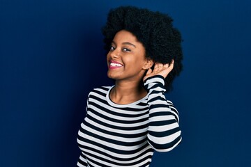 Young african american woman wearing casual clothes smiling with hand over ear listening an hearing to rumor or gossip. deafness concept.