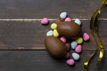 Chocolate Easter eggs with ribbon bows decoration on wooden vintage background.