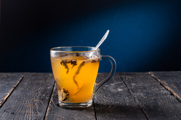 Transparent glass mug with tea. Tea leaves in a mug. Brewing tea in a mug. A teaspoon in a mug.
