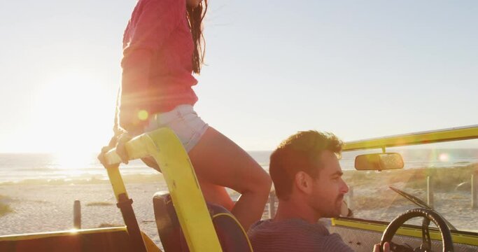 Happy caucasian couple sitting in beach buggy by the sea talking