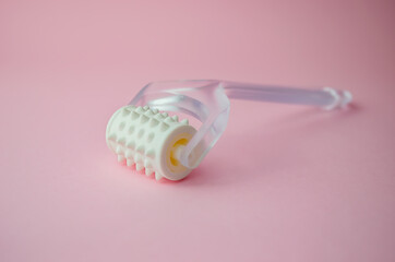 Roller face massager on a pink background. Skin care at home.