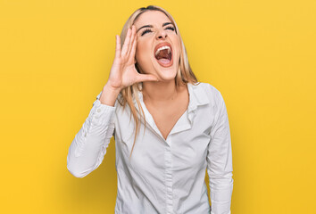 Young caucasian woman wearing casual clothes shouting and screaming loud to side with hand on mouth. communication concept.