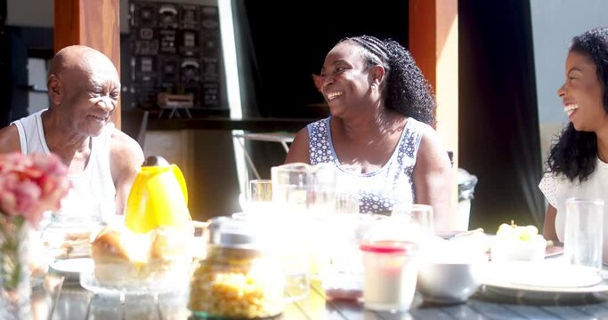 latinx grandparents at breakfast with their curly-haired granddaughter