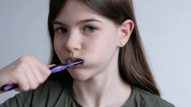 Little beautiful girl brushes her teeth with a toothbrush and toothpaste