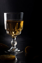 Clear crystal glass filled with golden liquor on dark background.