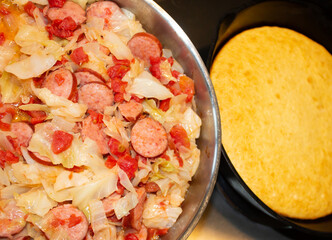 Southern style cooking of fried cabbage, sausage, onions and tomatoes. Cornbread baked in an iron skillet tops off this easy to prepare dinner meal