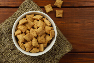 Chocolate breakfast pads in a white bowl, on burlap. Top view