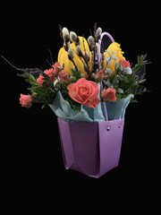 A bouquet of blossoming flowers in a beautiful vase. Tulips and roses in a beautiful package. Composition of spring flowers, on a black background