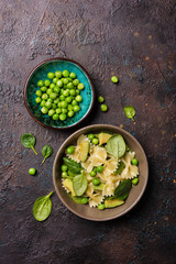 Farfalle pasta with green peas, avocado and spinach leaves