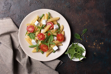 Penne pasta with cherry tomatoes, soft cheese, green beans, spinach and arugula leaves