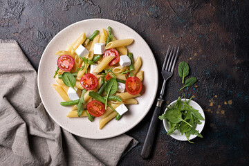 Penne pasta with cherry tomatoes, soft cheese, green beans, spinach and arugula leaves