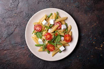 Penne pasta with cherry tomatoes, soft cheese, green beans, spinach and arugula leaves