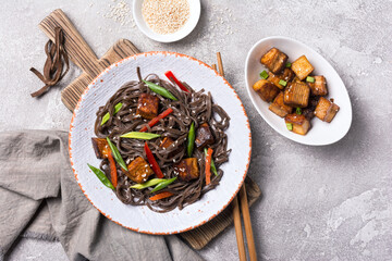 A dish of Asian cuisine. Soba noodles with red bell pepper, green onions and fried tofu cheese