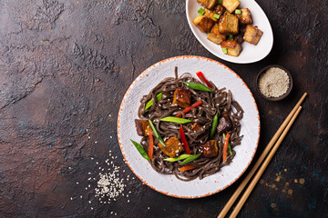 A dish of Asian cuisine. Soba noodles with red bell pepper, green onions and fried tofu cheese