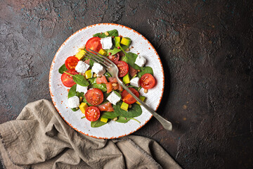 Healthy salad with fresh baby spinach, cherry tomatoes, avocado, soft cheese and salmon fish