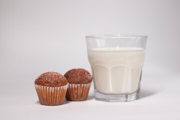 two little cupcakes or muffins in powdered sugar near a glass of milk. healthy breakfast. snack or lunch