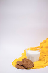 oat cookies with a glass of milk on yellow silk fabric isolated on white background