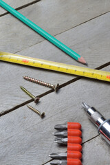 tape measure, screws and screwdriver lie on a wooden background. close-up.