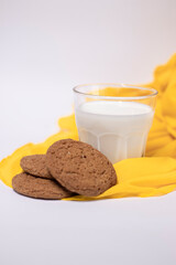oat cookies with a glass of milk on yellow silk fabric isolated on white background