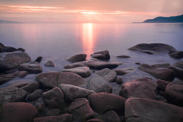  sunset landscape with stones conveys a romantic feeling on a desert coastline with water