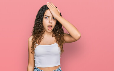 Teenager hispanic girl wearing casual clothes surprised with hand on head for mistake, remember...