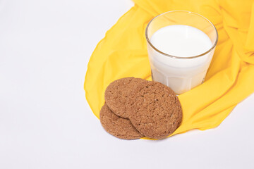 oat cookies with a glass of milk on yellow silk fabric isolated on white background