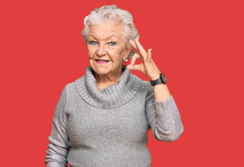 Senior grey-haired woman wearing casual winter sweater smiling positive doing ok sign with hand and fingers. successful expression.