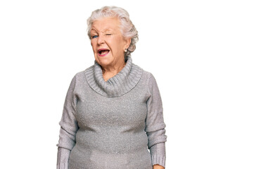 Senior grey-haired woman wearing casual winter sweater winking looking at the camera with sexy...