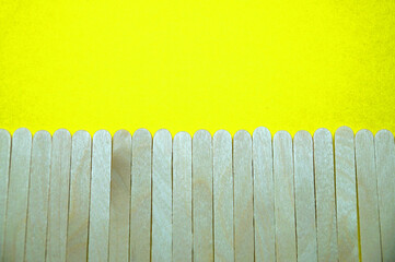 wooden ice cream sticks imitating a fence on a yellow background blank copy space