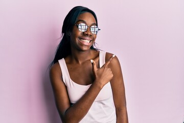 Young african american woman wearing casual clothes and glasses smiling cheerful pointing with hand...