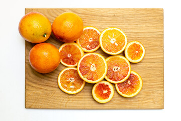 Blood Sicilian oranges on wooden cutting board. Sliced ripe juicy citrus fruits on white background. Top view.