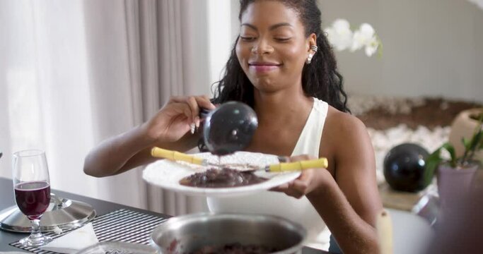 Beautiful latinx woman eating feijoada - typical brazilian food