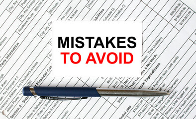 Text Mistakes To Avoid written on a business card lying on financial tables with a blue metal pen