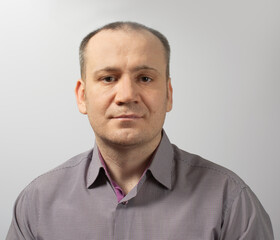 Fototapeta premium confident slightly unshaven man in purple shirt on gray background. 