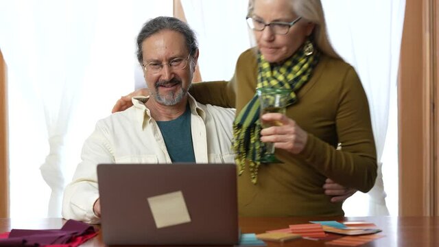 Happy smiling mature couple using laptop computer buying online with credit card and talk with seniors at home.