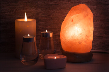 Himalayan salt lamp with, candles in dark room. Spa, relax concept.