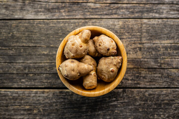 Raw jerusalem artichoke. Topinambur vegetable root in wooden bowl.