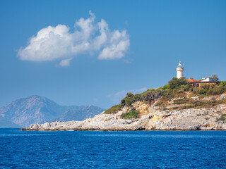 Fototapeta na wymiar view to rock cliff at sea with alone lighthouse under blue sky with white cloud