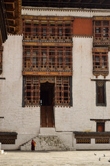 A monk walking alone in the inner courtyard of Tashichho Dzong, a buddhist monastery in the capital of Bhutan, Thimphu.